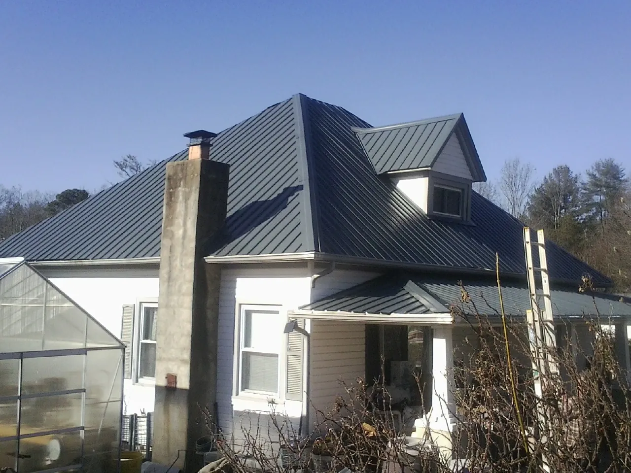 Dark blue standing seam metal roof on a white farmhouse with dormer — Slate & Tile Roof Repair by Roofing Brothers in Talisheek