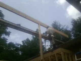 Carpenter setting a ridge beam over a new addition frame — Ice Dam Removal by Roofing Brothers in Talisheek