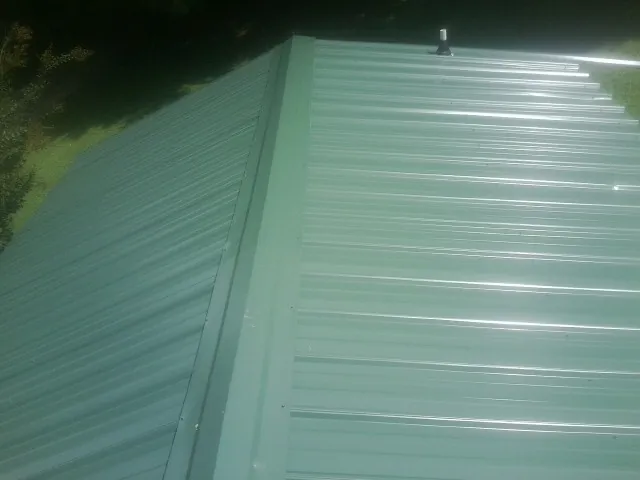 New green metal panels meeting at the ridge of a roof — Flat Roof Repair work by our crew in Talisheek
