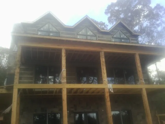 Dormers and porch framing on a large log home under construction — Roof Coating work by our crew in Talisheek