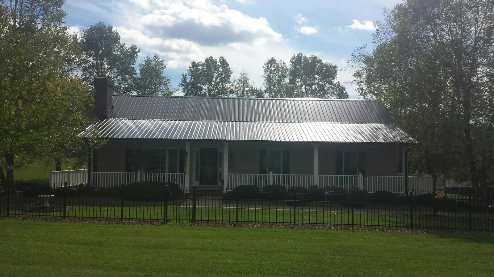 Gray metal roof on a brick ranch with a full width front porch — Gutter Guard Installation work by our crew in Talisheek