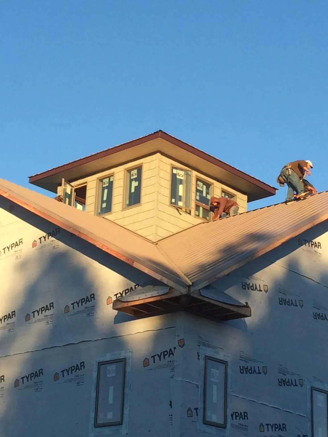 Roofers working around a rooftop cupola on a new metal roof at sunset — Roof Waterproofing in Talisheek by Roofing Brothers